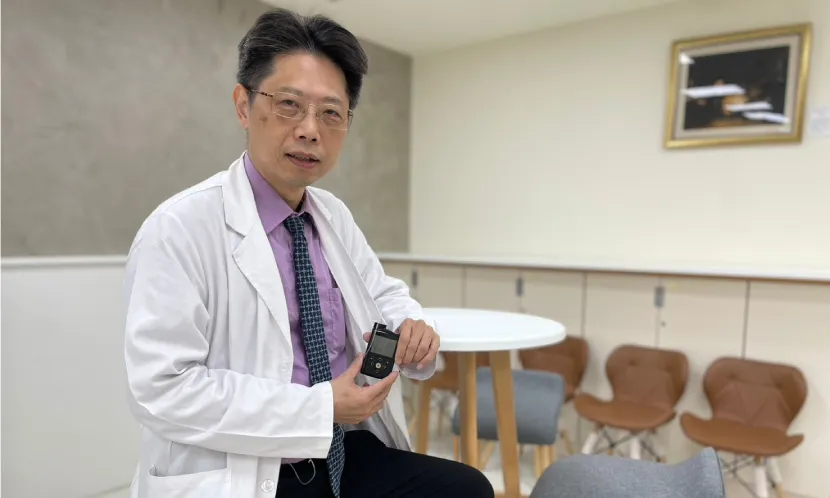 林嘉鴻目前每天配戴智慧閉環系統,他手中拿的則是胰島素幫浦主機,平常會收在口袋內。 圖片來源 / 鄧桂芬攝